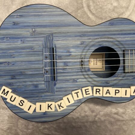 Ukulele, jonka päällä on kirjaimet musiikkiterapia